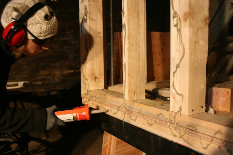 Applying construction adhesive to the studs